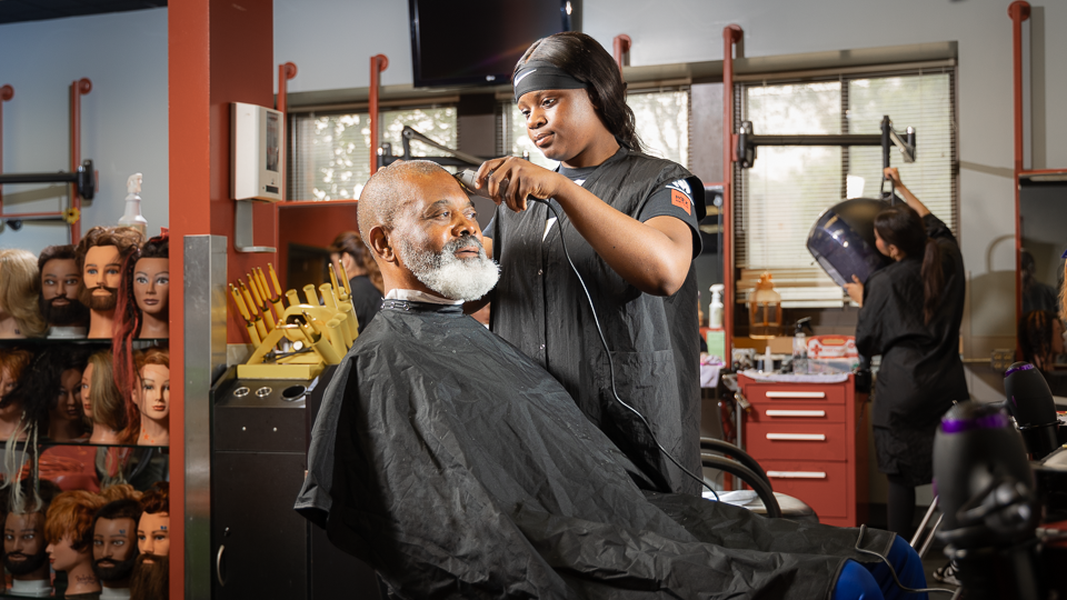 man getting a haircut from a student