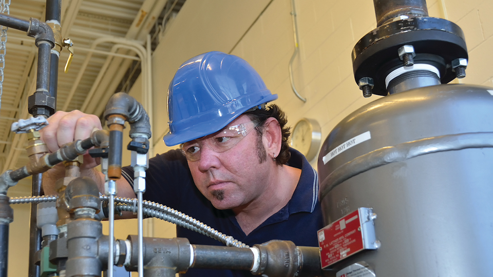 man in boiler room checking gauge